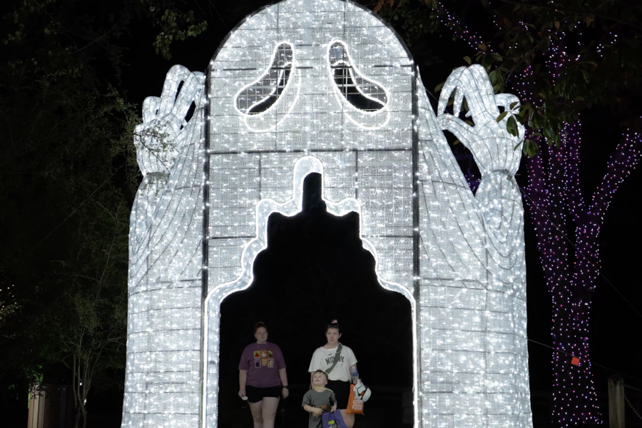A family walks through a glowing Ghost archway structure at night