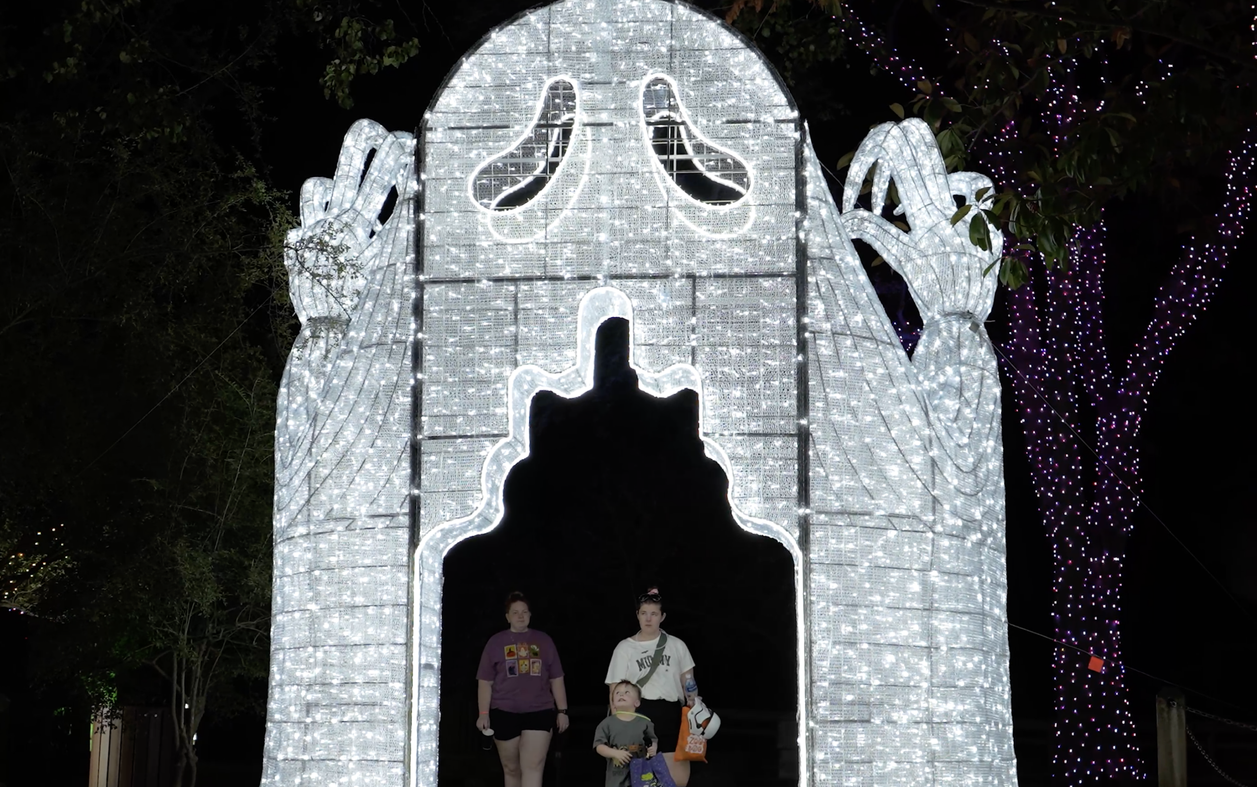 A family walks through a glowing Ghost archway structure at night
